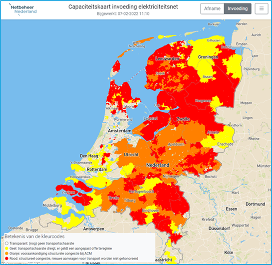 Kaart van Nederland met rood en oranje gekleurde regio's die netcongestie aangeven, met een bouwkraan op de voorgrond